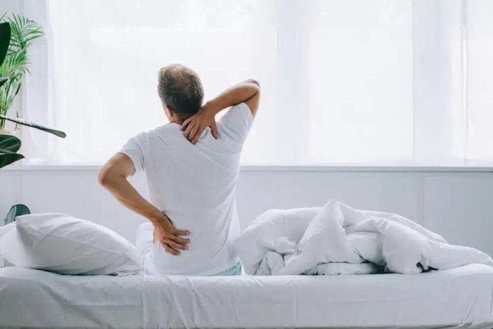 Man sitting on bed with back pain